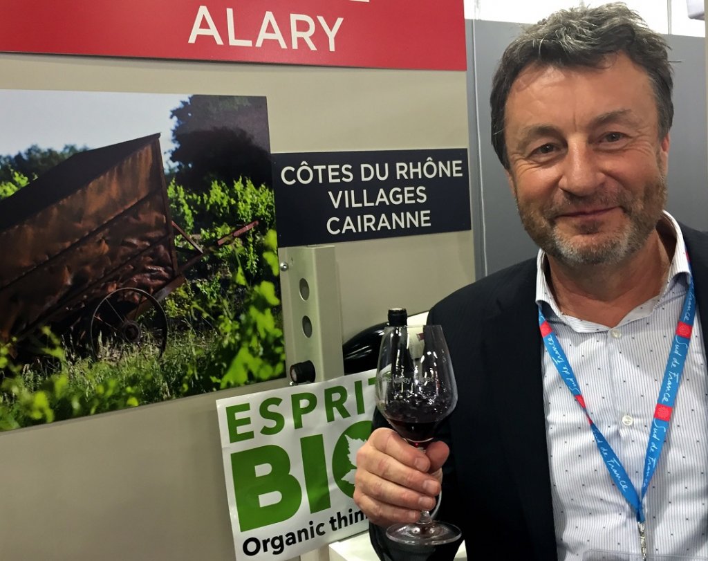 Sur son stand, à Vinisud, Denis Alary n’a pas eu le temps de modifier le panneau affichant l’appellation Côtes du Rhône Village. Il est vrai que, pour l’heure, on attend la publication du décret au Journal Officiel pour devenir Cru (Photo M.E.)