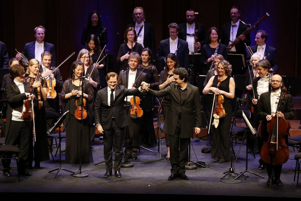 Renaud Capuçon et Rolando Villazon aux saluts devant les instrumentistes de la Camerata Salzburg avec, à l’extrême gauche sur la photo, le konzertmeister du soir, Benjamin Marquise Gilmore. (Photo Caroline Doutre)