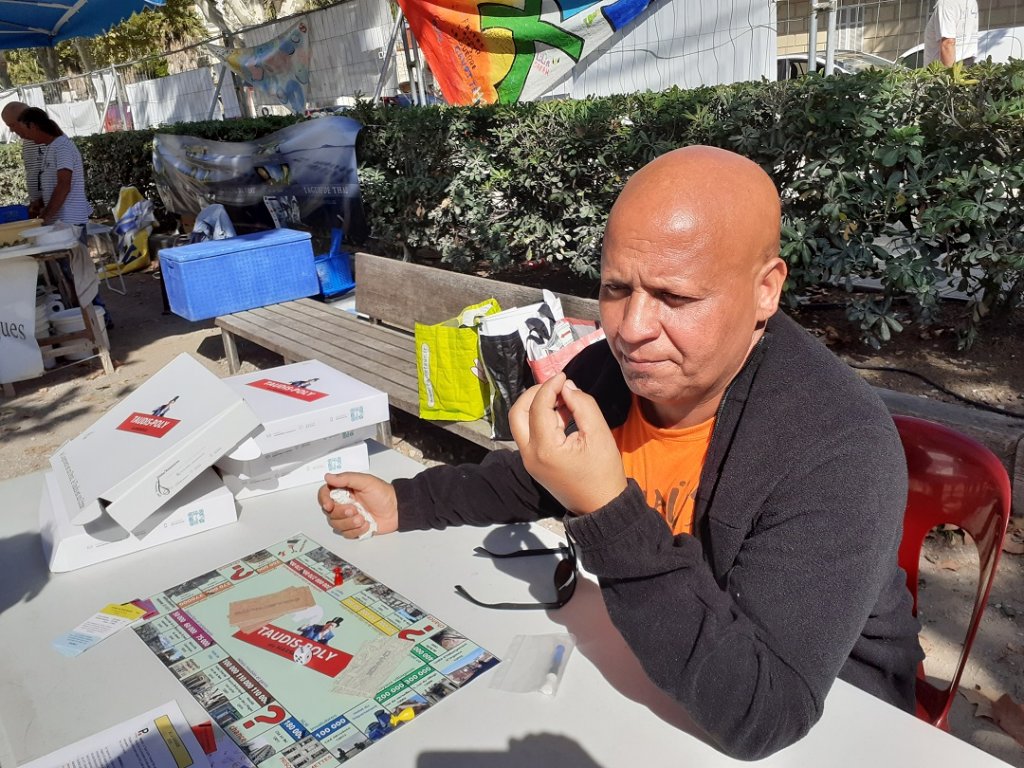 Fathi Bouaroua a présenté le Taudis-Poly, un jeu qui s’inspire du "Monopoly" mais pour montrer les adresses et les situations du mal logement à Marseille (Photo M.B.)