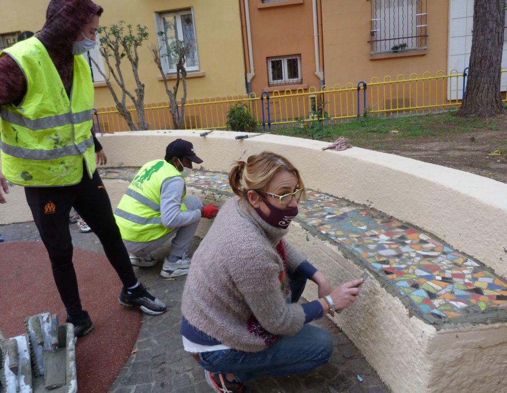 Des jeunes de l’équipe de Tapaj et la mosaïste Paola Cervoni lors de l'habillage de 2 bancs au sein d'une résidence à Marseille ©Groupe SOS