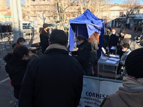 Sur une place, tente, table pliante et deux chaises, barrières de sécurité et banderole forment le centre de vaccination ©Joël Barcy