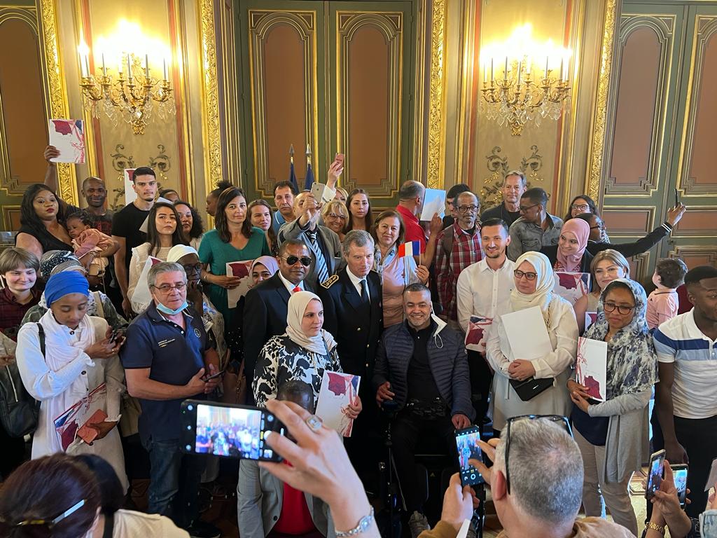 Le préfet Christophe Mirmand entouré de femmes, d'enfants et d'hommes qui affichent avec fierté le fameux document qui atteste qu'ils sont désormais Français ©Joël Barcy